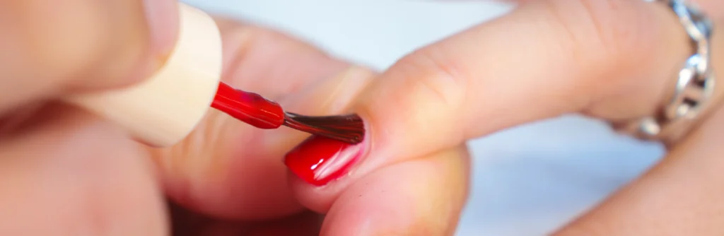 Application de vernis rouge sur un ongle